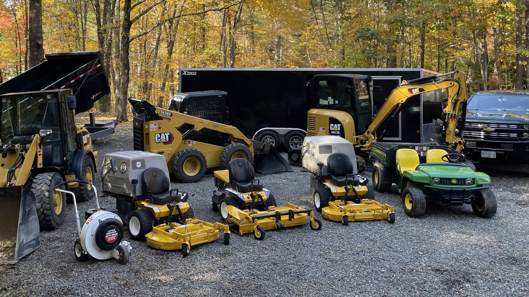 The LandPro fleet lined up on gravel in front of fall foliage